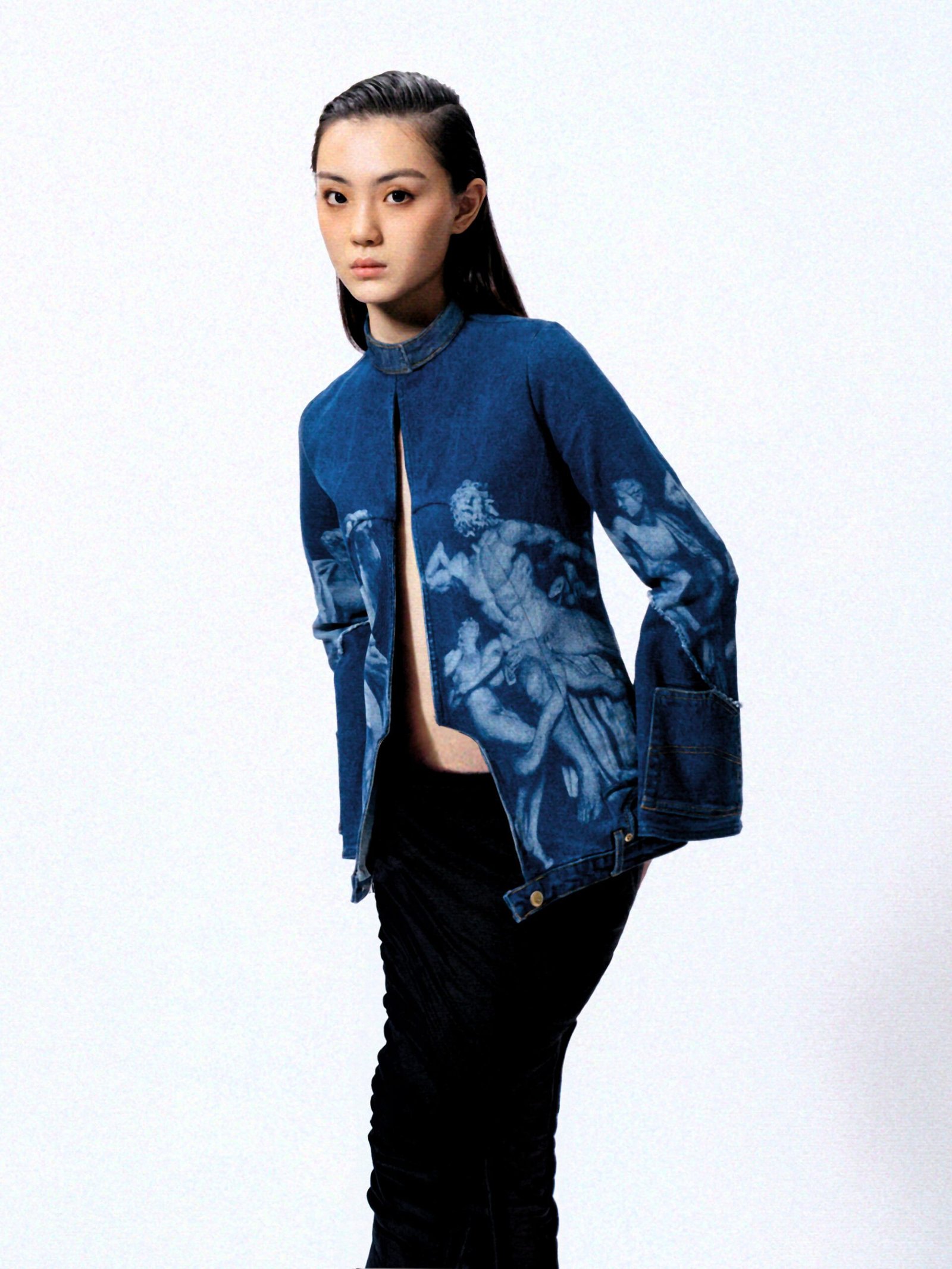 model in studio photoshoot setting wearing a blue Denim Upcycled Jacket laser etched Greek statue print. editorial high-fashion image.